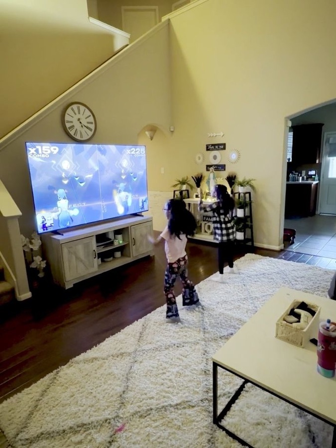 Two sisters dancing in the living room with combo scores on screen
